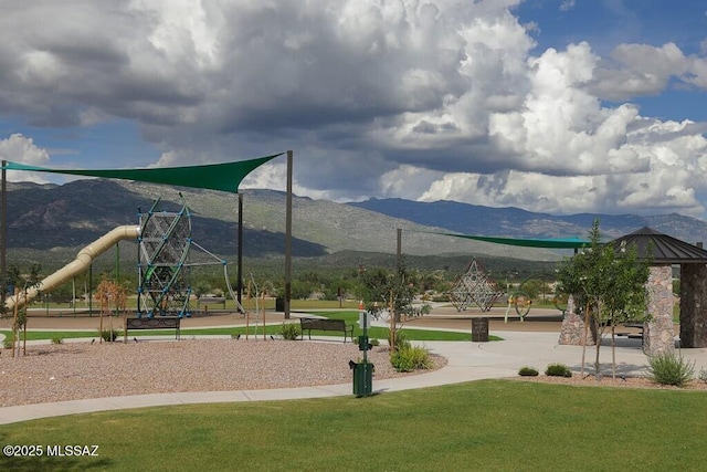 view of property's community with playground community, a mountain view, and a lawn