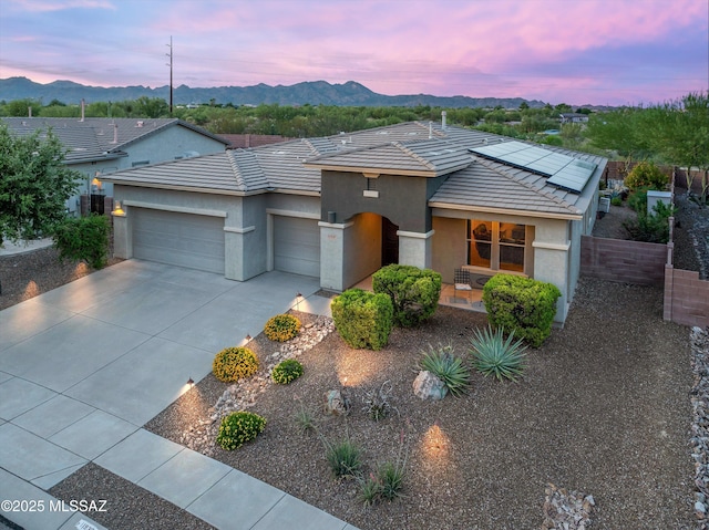 view of front of house featuring a garage, a mountain view, and solar panels