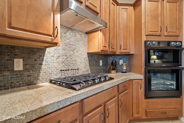 kitchen featuring backsplash, multiple ovens, and stainless steel gas stovetop