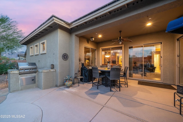 patio terrace at dusk with area for grilling and exterior kitchen