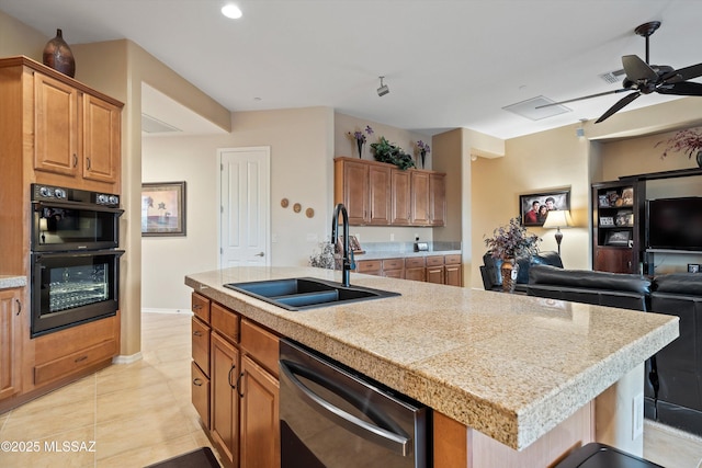 kitchen with double oven, an island with sink, sink, stainless steel dishwasher, and light tile patterned floors