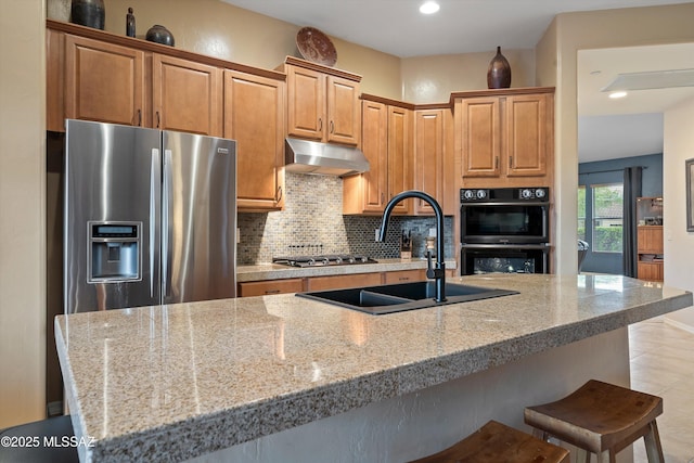 kitchen with light stone counters, stainless steel appliances, sink, and decorative backsplash