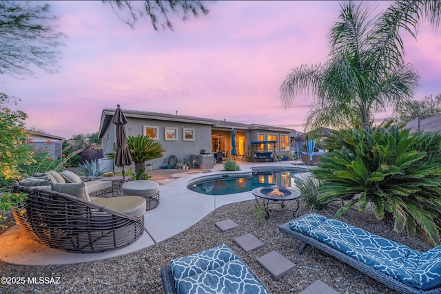 pool at dusk with a fire pit and a patio area