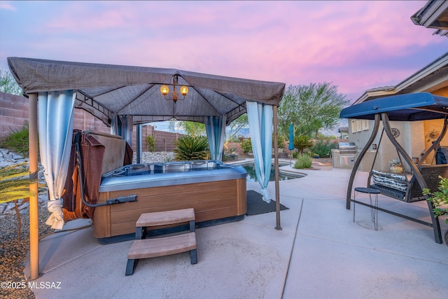 patio terrace at dusk with a hot tub and a gazebo