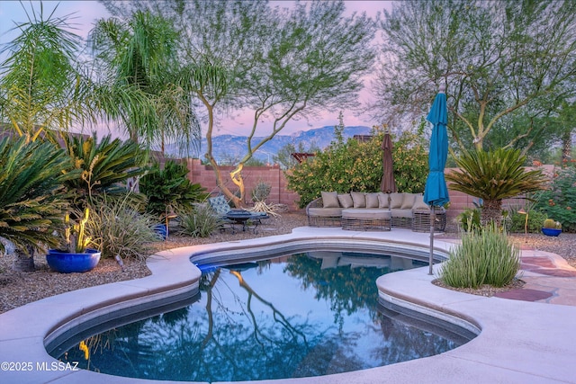 pool at dusk featuring a patio and a mountain view