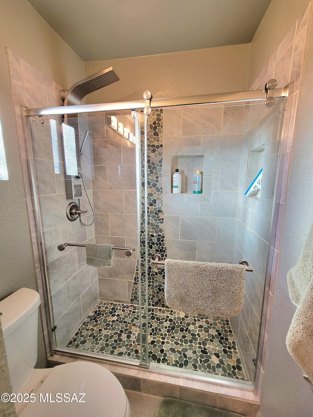 bathroom featuring toilet and a shower with door