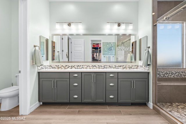 bathroom featuring vanity, toilet, and a shower with door