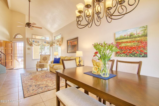 dining space with light tile patterned floors, high vaulted ceiling, stairway, and ceiling fan with notable chandelier