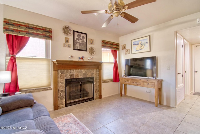 living room with ceiling fan, tile patterned floors, a tile fireplace, and a healthy amount of sunlight