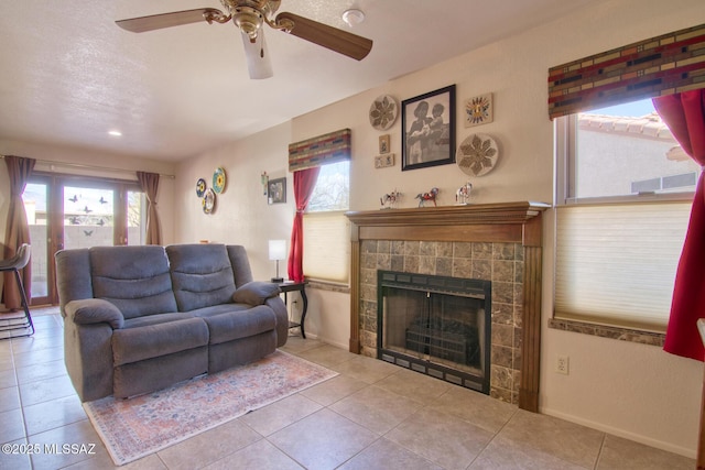 tiled living room featuring plenty of natural light, baseboards, a textured ceiling, and a tile fireplace