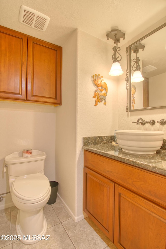 bathroom with visible vents, toilet, vanity, baseboards, and tile patterned floors