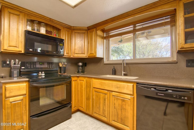 kitchen with black appliances, light tile patterned floors, light countertops, and a sink