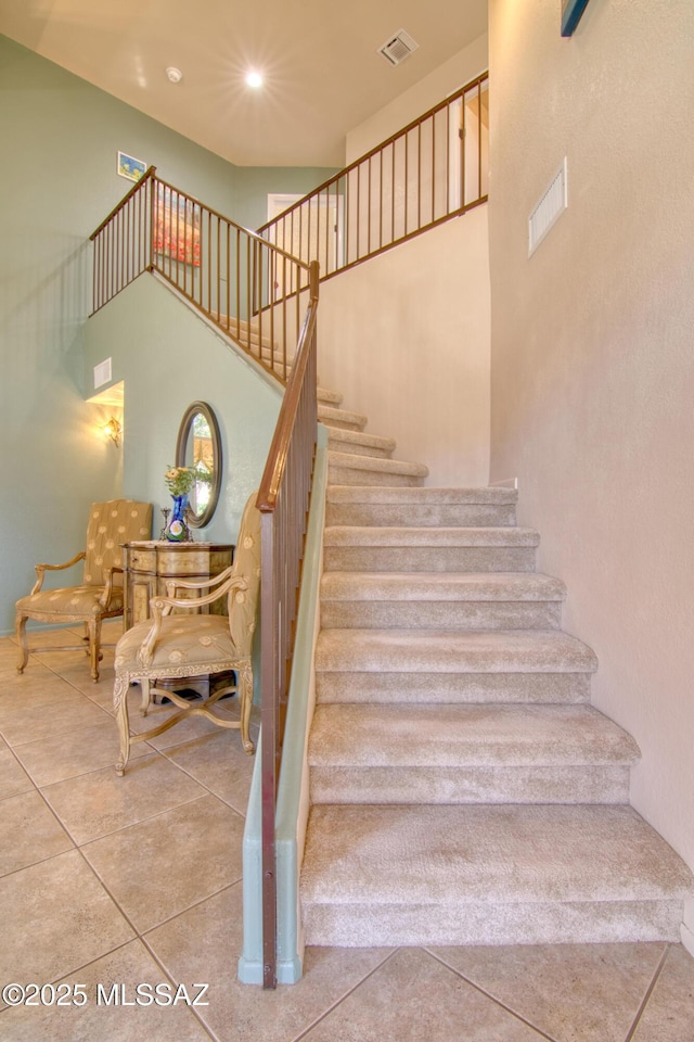 staircase featuring tile patterned flooring, a towering ceiling, visible vents, and recessed lighting