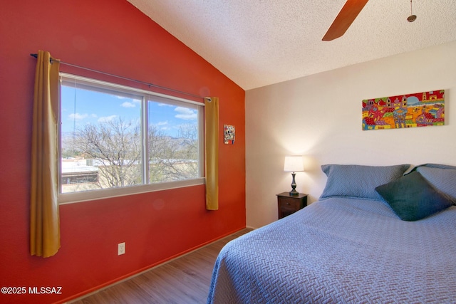 bedroom with lofted ceiling, a ceiling fan, a textured ceiling, wood finished floors, and baseboards