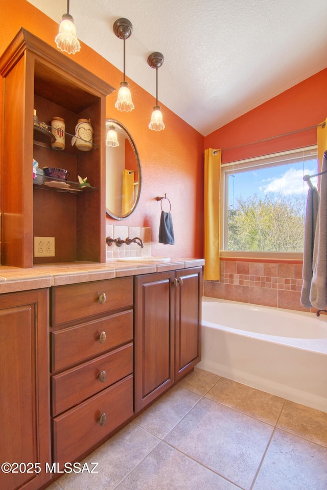 full bath featuring a garden tub, vaulted ceiling, vanity, a textured ceiling, and tile patterned flooring