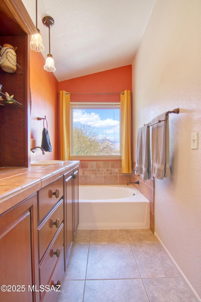 bathroom with a textured wall, lofted ceiling, tile patterned floors, a garden tub, and a textured ceiling