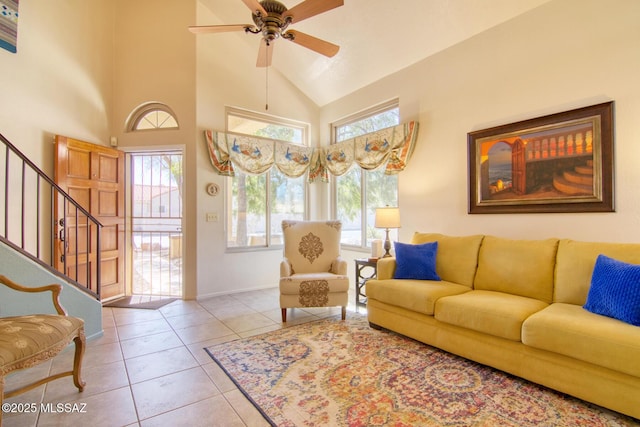 tiled living area featuring baseboards, stairs, high vaulted ceiling, and a ceiling fan