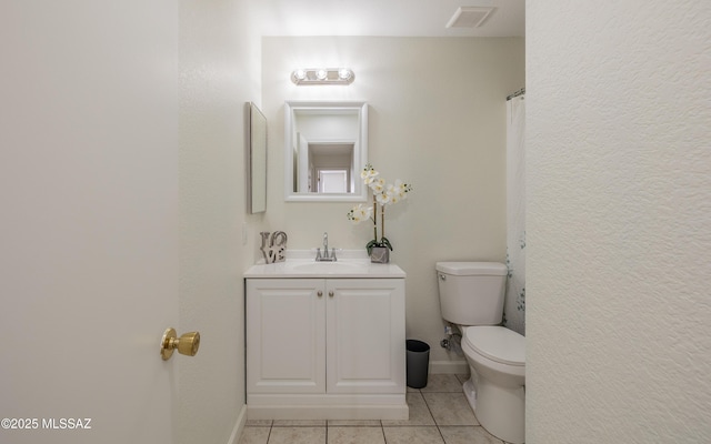 bathroom featuring toilet, vanity, baseboards, visible vents, and tile patterned floors