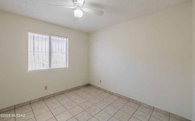 spare room featuring a textured ceiling, ceiling fan, and light tile patterned floors