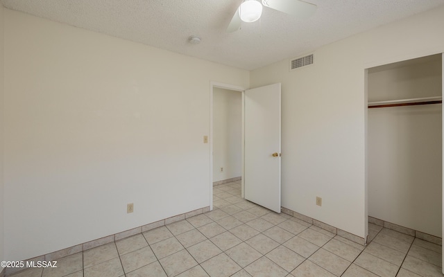 unfurnished bedroom with light tile patterned floors, a closet, visible vents, a ceiling fan, and a textured ceiling