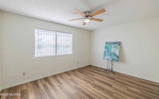 empty room featuring a textured ceiling, ceiling fan, wood finished floors, and baseboards