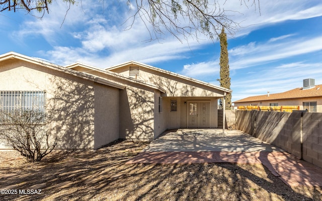 view of side of property featuring stucco siding, fence, cooling unit, and a patio