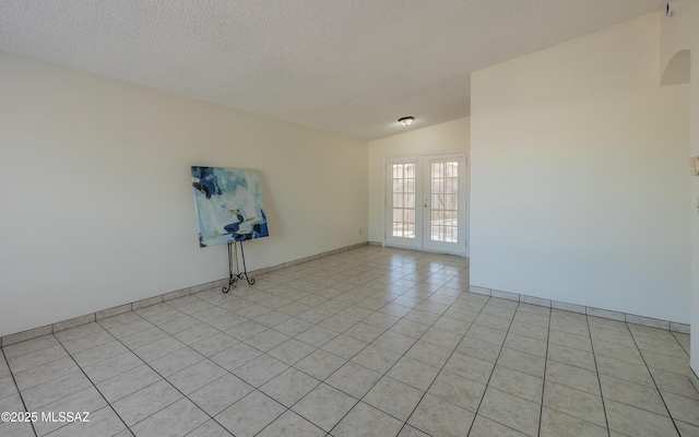 unfurnished room with french doors, light tile patterned floors, lofted ceiling, a textured ceiling, and baseboards