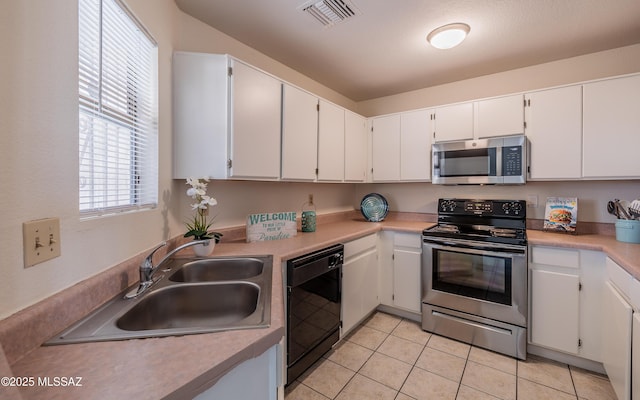 kitchen with light tile patterned floors, visible vents, white cabinets, stainless steel appliances, and a sink