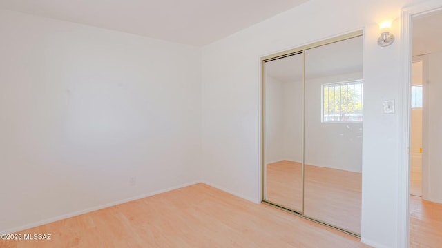 unfurnished bedroom featuring light wood-type flooring and a closet