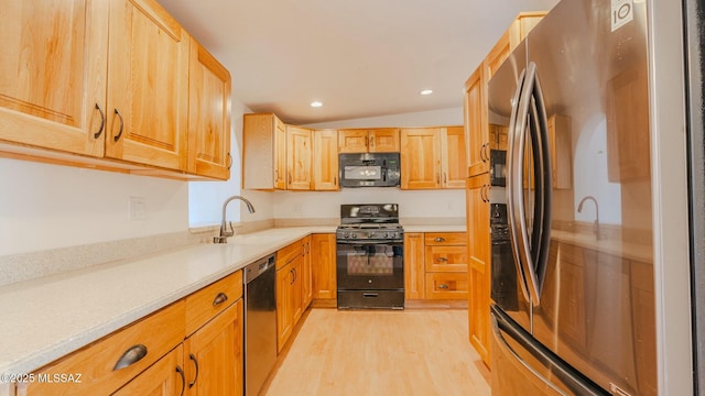 kitchen with sink, black appliances, light hardwood / wood-style floors, light brown cabinetry, and vaulted ceiling