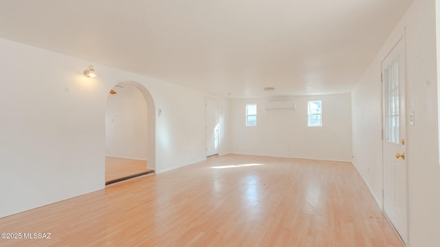 unfurnished room with a wall unit AC and light hardwood / wood-style flooring