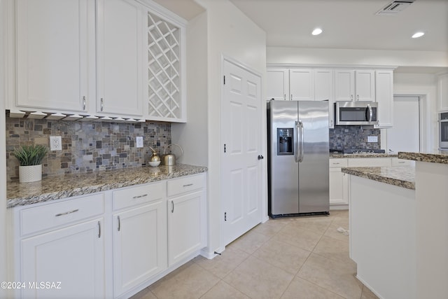 kitchen featuring light stone countertops, white cabinetry, appliances with stainless steel finishes, and light tile patterned floors