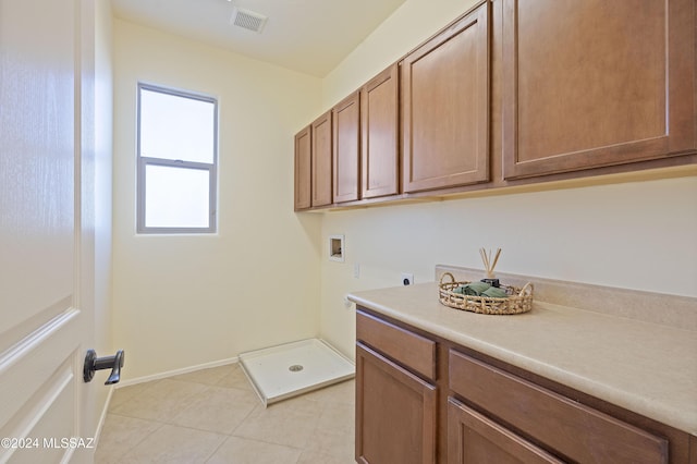 laundry area featuring hookup for a washing machine, electric dryer hookup, light tile patterned floors, and cabinets