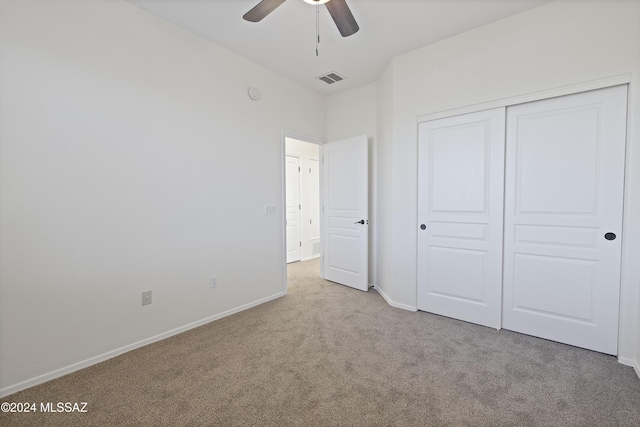 unfurnished bedroom with light colored carpet, a closet, and ceiling fan