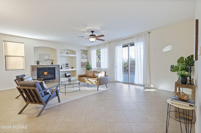 tiled living room featuring ceiling fan, a fireplace, and built in features