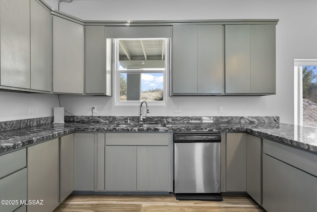 kitchen featuring gray cabinets, dishwasher, sink, and dark stone countertops