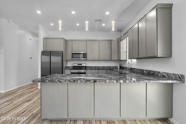 kitchen featuring gray cabinetry, decorative light fixtures, kitchen peninsula, and appliances with stainless steel finishes