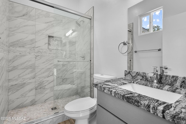 bathroom featuring vanity, a shower with shower door, and toilet