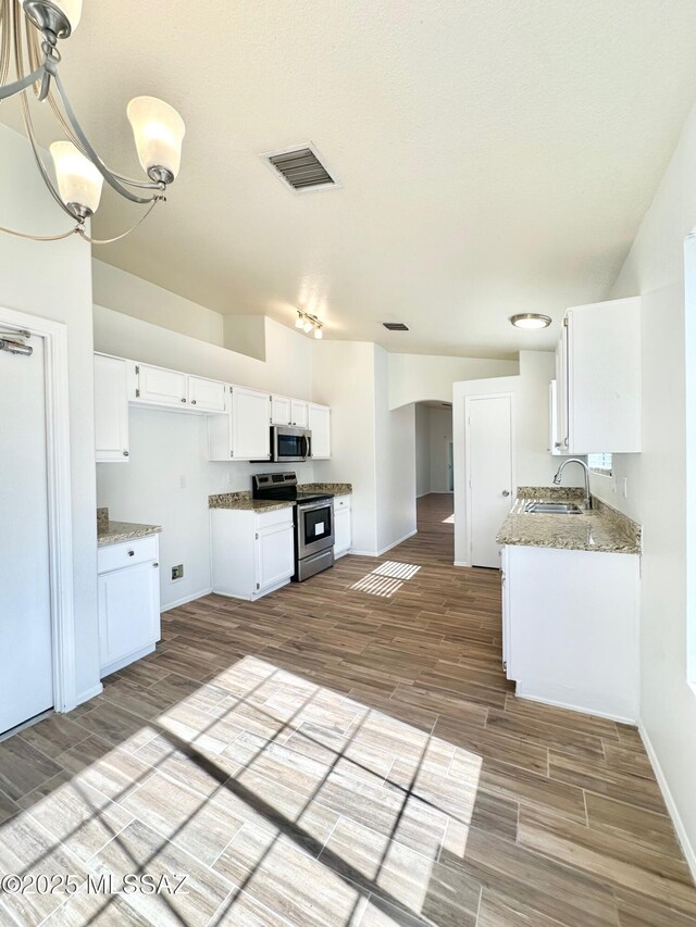 kitchen with light wood finished floors, visible vents, appliances with stainless steel finishes, white cabinetry, and a sink