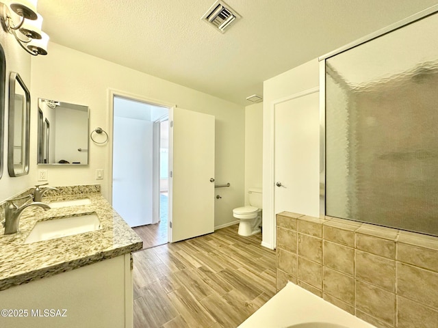 bathroom featuring a sink, visible vents, toilet, and wood finished floors