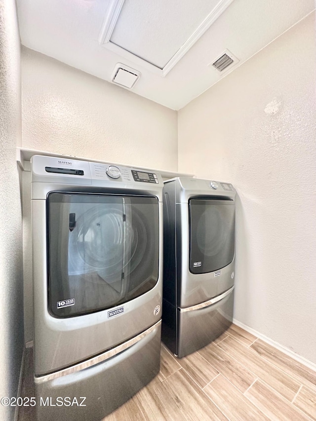 washroom with visible vents, wood tiled floor, baseboards, laundry area, and washing machine and clothes dryer