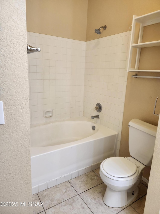 bathroom with tile patterned flooring, tiled shower / bath combo, and toilet
