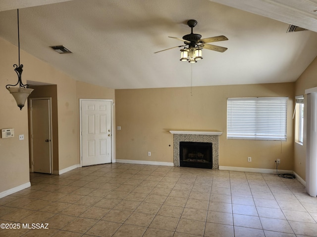 unfurnished living room with light tile patterned floors, ceiling fan, a textured ceiling, a tiled fireplace, and vaulted ceiling