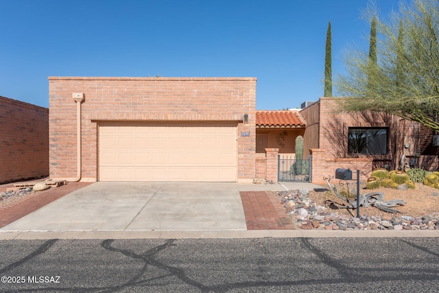 pueblo revival-style home featuring a garage, a tile roof, fence, concrete driveway, and stucco siding