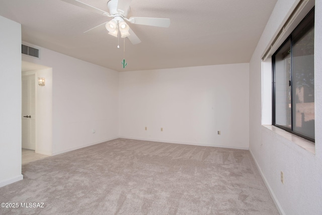 spare room with light colored carpet, ceiling fan, visible vents, and baseboards