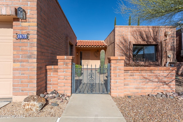 view of front facade with a garage, a tile roof, a gate, fence, and brick siding