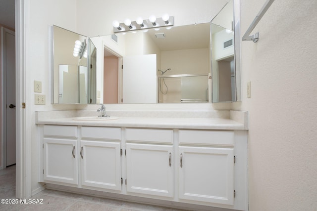 full bathroom featuring a shower with door, tile patterned floors, visible vents, and vanity