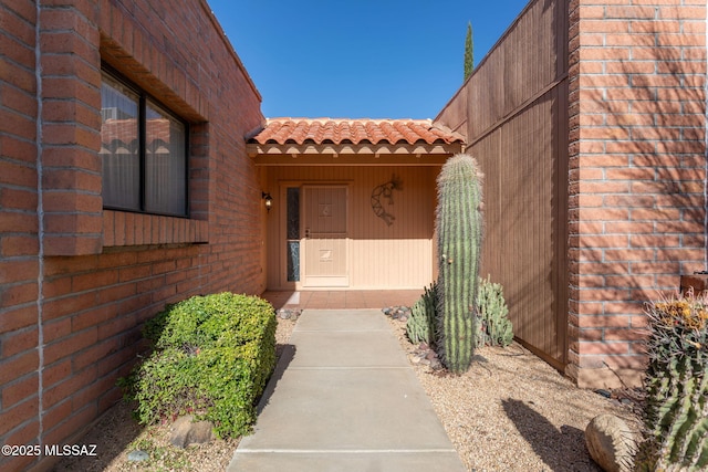 property entrance featuring a tile roof and brick siding