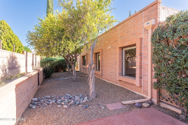 view of side of property with a fenced backyard and brick siding