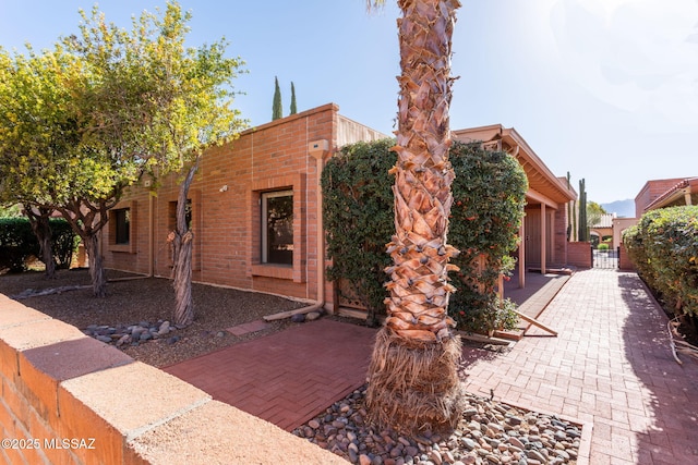 view of front of home with fence, a patio, and brick siding